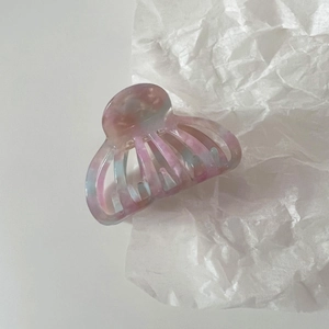 Detail of pink and blue acetate shell hair claw clip with marble texture on white background