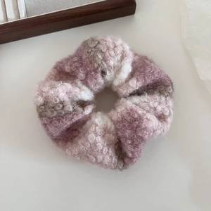 Détail d'un chouchou en laine pelucheuse à carreaux roses et gris, texture douce