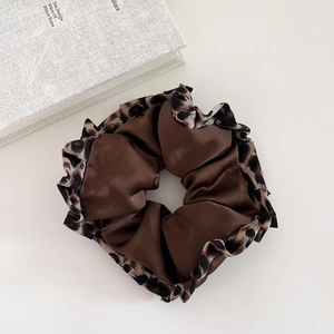 Vintage leopard print scrunchie with brown satin fabric on white background near a book