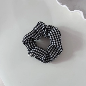 Macro detail of black and white houndstooth fabric scrunchie with elegant pleats