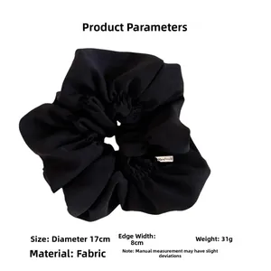 Detail view of large 17cm black scrunchie with handmade tag showing fabric texture