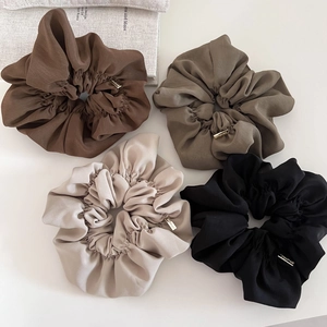 Detail of four large earth-toned scrunchies with elegant gold metal handmade tags