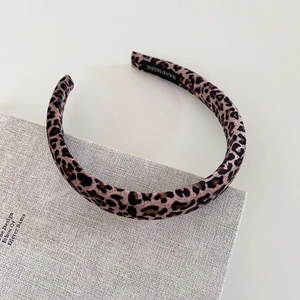 Detail of leopard print velvet headband with handmade label on a textured book