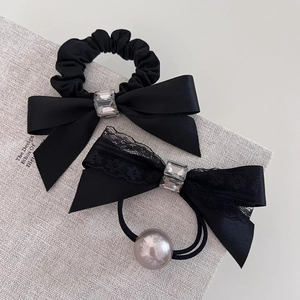 Close-up of black satin bow hair ties with sparkling rhinestones and pearl details