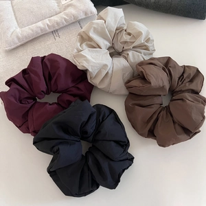 Flat lay of oversized puffy scrunchies in burgundy, cream, brown, and black colors