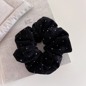 Detail of black polka dot scrunchie in ribbed corduroy fabric on a minimalist background