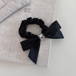 French black satin bow hair tie with rhinestone and pearl on a textured book