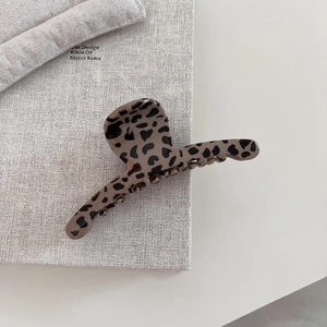 Detail view of a vintage brown leopard print hair claw clip on a minimalist background