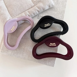 Three matte hair claws in pink, black, and burgundy with French style lettering design