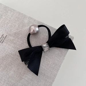 Close-up of black satin bow hair tie with lace detail and silver-grey glossy bead accent