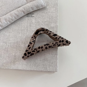 Close-up of geometric leopard print hair claw clip on a book background with metal spring