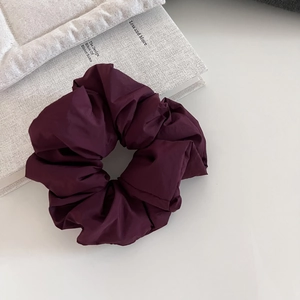 Detailed view of dark purple puffy scrunchie showing premium pleated fabric texture