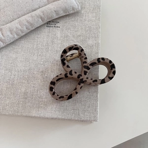 Detailed view of leopard print hair claw clip with golden metal spring on book