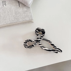 Minimalist zebra print hair claw clip with sleek twist design on a clean white background