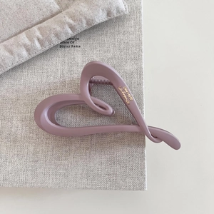 Macro detail of heart hair claw clip with matte finish and gold script lettering