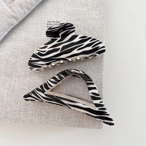 Detailed view of black and white zebra pattern hair claws with elegant geometric designs