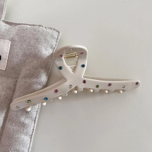 French style cream acetate hair claw clip with colorful rhinestones on white table