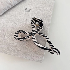 Detail of zebra pattern acetate hair claw clip with gold metal spring on a grey book