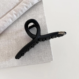 Detail shot of a matte black hair claw with gold Barrette La France text on fabric