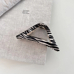 Close-up of zebra pattern triangle hair claw clip with golden metal spring detail