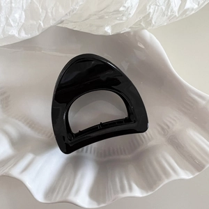 Macro shot of minimalist black triangle hair claw with cutout on shell tray