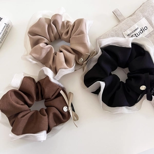 Dettaglio di elastici per capelli con fiocco premium in nero e beige con organza