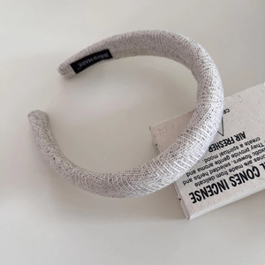Detail of light gray tweed headband showing handmade label and woven texture finish