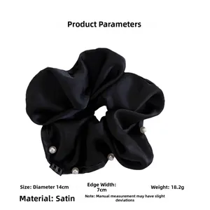 Detail showing a 14cm black satin scrunchie with white pearls and size specifications