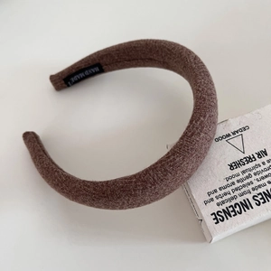Macro detail of dark brown wool headband showing textured fabric and handmade label