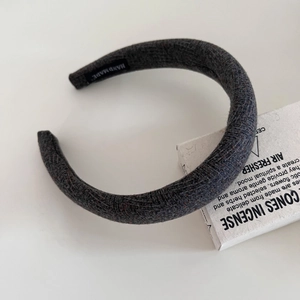Detail of dark grey tweed headband featuring a handmade label and textured fabric