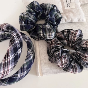 Detail of plaid headband and scrunchies set in British wool fabric on a white desk