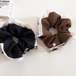 Dettaglio di elastici scrunchie in tessuto nero e marrone con organza e accenti dorati