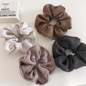 Detail of four herringbone tweed hair scrunchies in oatmeal and earth tones set