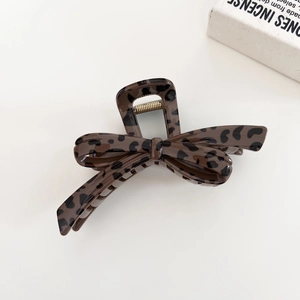 Polished leopard print acetate hair claw clip with elegant bow structure on white background
