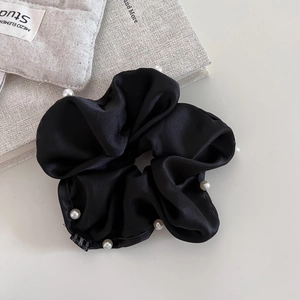 Detail showing high-quality black satin hair scrunchie decorated with elegant white pearls