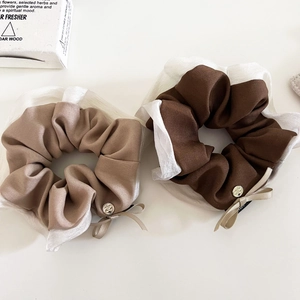 Dettaglio di elastici per capelli in tessuto con bordo in organza e fibbia metallica