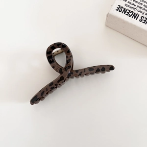 Detail of a large leopard print hair claw clip with golden spring and resin finish