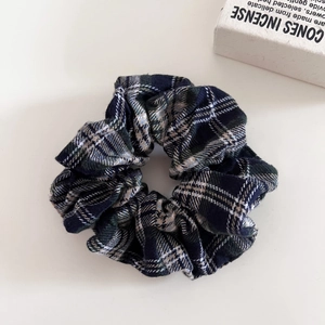 Close-up of navy and green plaid hair scrunchie with soft fabric folds and retro pattern