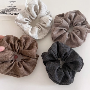 Detail of four oatmeal toned wool scrunchies with herringbone weave texture for winter