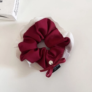 Dettaglio dell'elastico in raso bordeaux con fiocco e fibbia in metallo argento