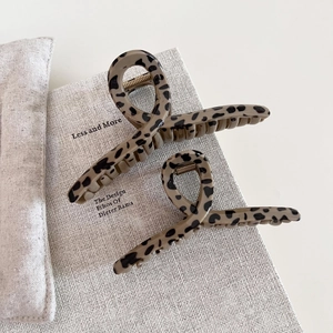 Detail view of two vintage leopard print hair claws on a minimalist textured background