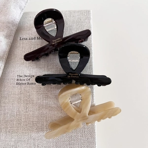 Trio of acetate shark hair claws in chocolate, black, and marble cream for elegant styling
