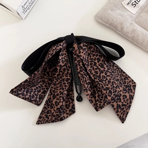 Detalle de pinza para el pelo con estampado de leopardo y elegantes lazos de satén negro