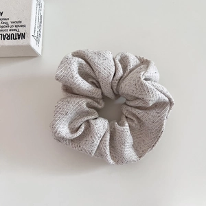 Close-up of oatmeal wool fabric hair scrunchie with detailed woven texture and soft feel