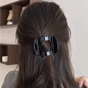 Minimalist glossy black square hollow hair claw clip worn on a woman's hair in a back view