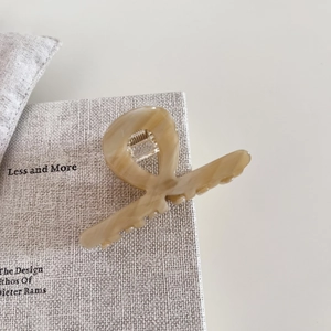 Detail of medium acetate hair claw in beige marble texture with silver spring mechanism