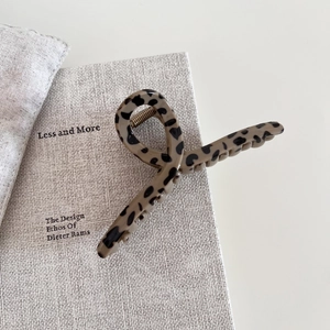 Detail of leopard print hair claw clip made of acetate on a textured book surface