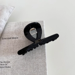 Detail of a shiny black acetate claw clip with gold Barrette la France lettering