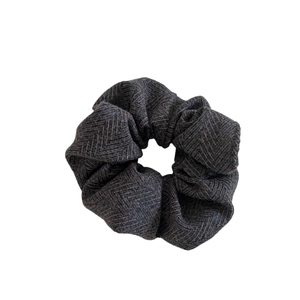 Herringbone pattern scrunchie in deep grey and brown wool-like fabric on white background