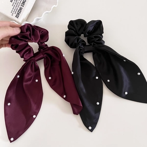 Detail of satin bow scrunchies in wine red and black with elegant pearl accents